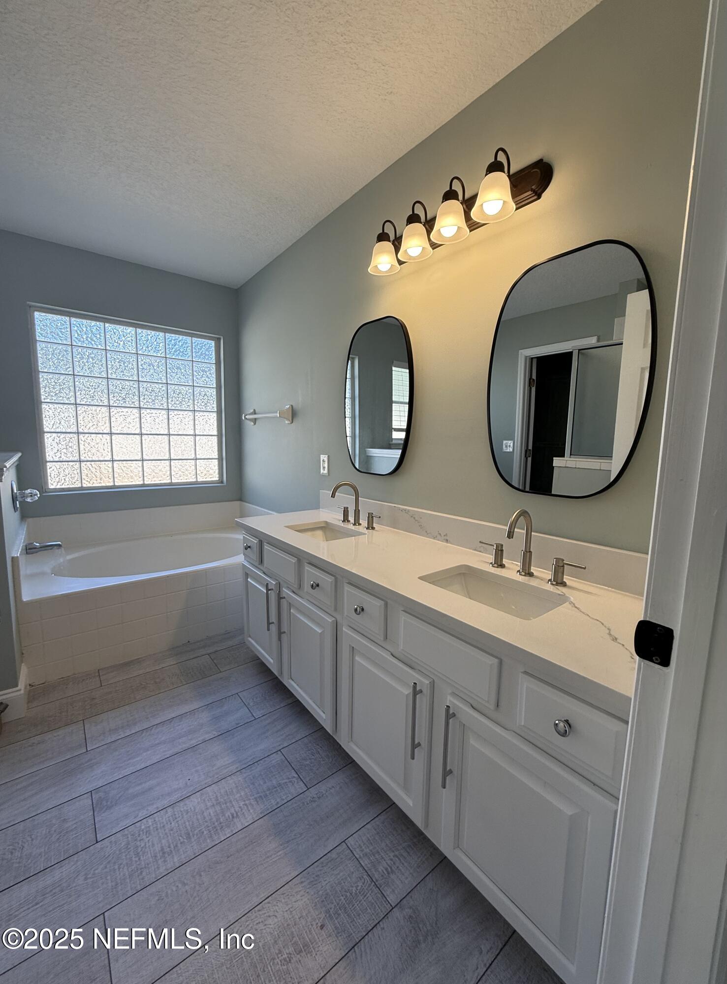 677 MacKenzie Circle St. Augustine, FL 32092 - Photo 42 of 92 a bathroom with a double vanity sink and mirror with bathtub