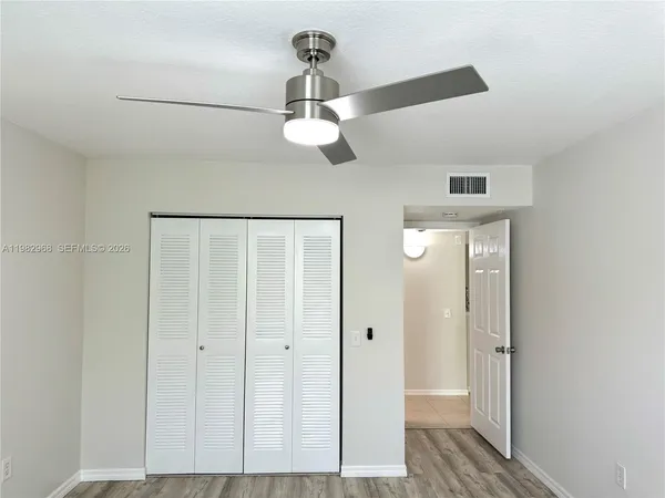 a view of a hallway with chandelier fan and wooden floor