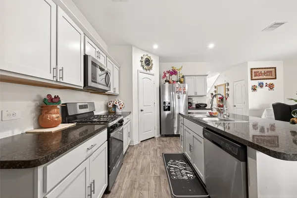 a kitchen with stainless steel appliances granite countertop a refrigerator a stove and a sink with wooden floor