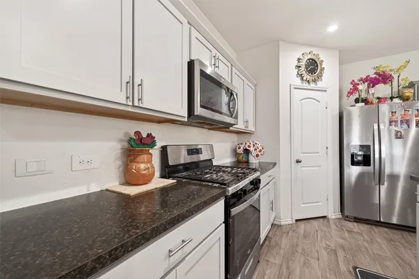 a kitchen with stainless steel appliances granite countertop a sink dishwasher a stove and a refrigerator with wooden floor