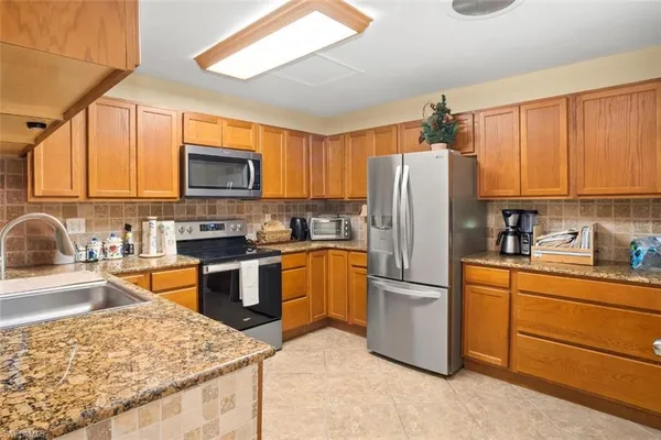a kitchen with granite countertop wooden cabinets a stove top oven and stainless steel appliances