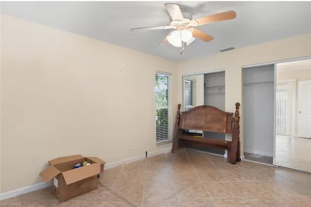 an empty room with a chandelier fan and closet area