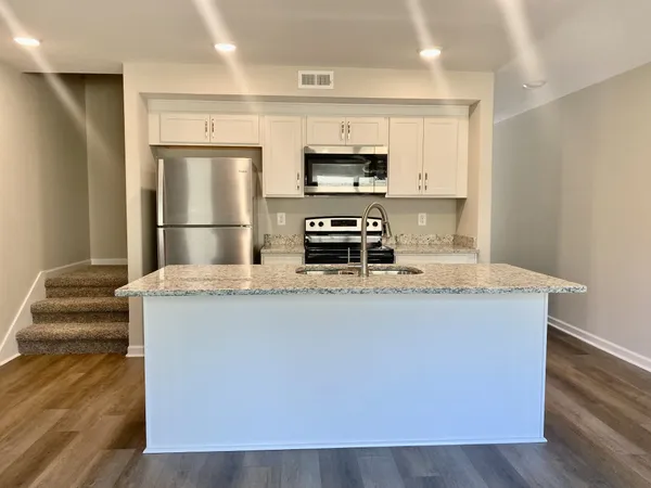 a kitchen with stainless steel appliances a refrigerator a stove a microwave and white cabinets