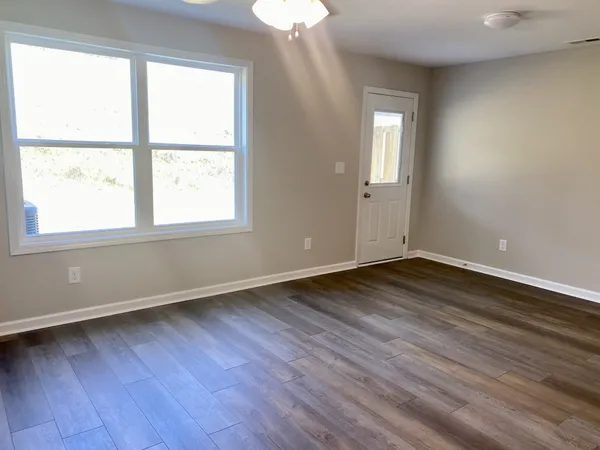 an empty room with wooden floor and windows