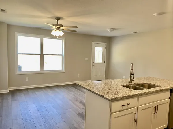 a kitchen with granite countertop white cabinets and a wooden floor