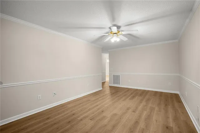 an empty room with wooden floor and fan