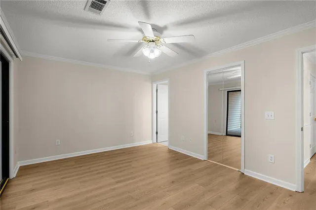 an empty room with wooden floor fan and windows