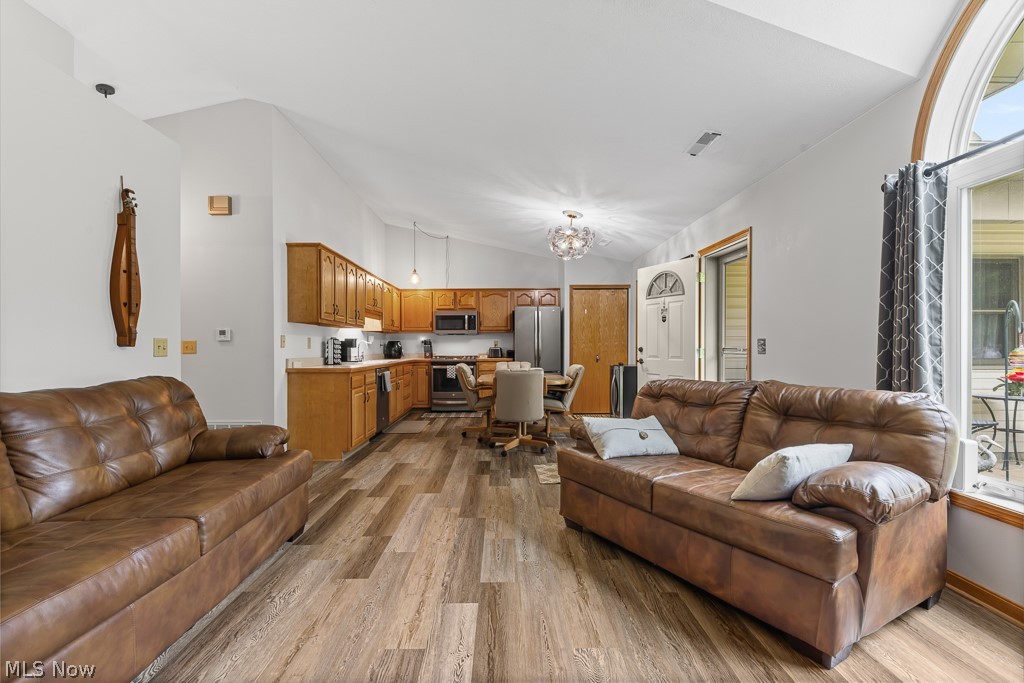 808 Ryan Road, Unit 14 Medina, OH 44256 - Photo 9 of 40 Open-concept living area featuring vaulted ceilings, wood-finish flooring, and a kitchen with wood cabinetry and light-toned countertops