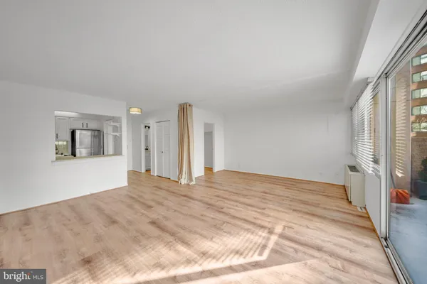 a view of empty room with wooden floor and fan