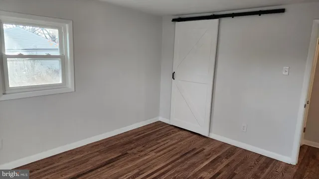 a view of an empty room with wooden floor and window