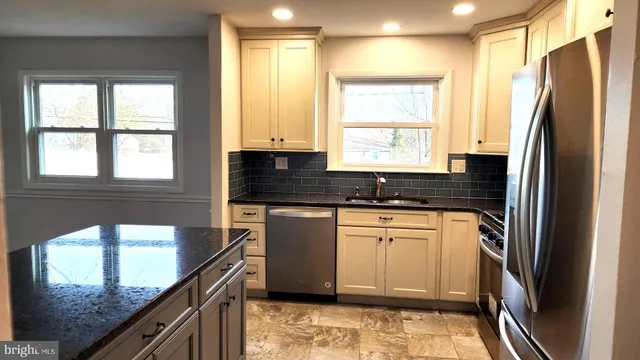 a kitchen with stainless steel appliances granite countertop a refrigerator a sink and white cabinets