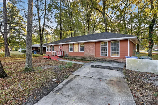 a view of a yard in front of a house with large trees