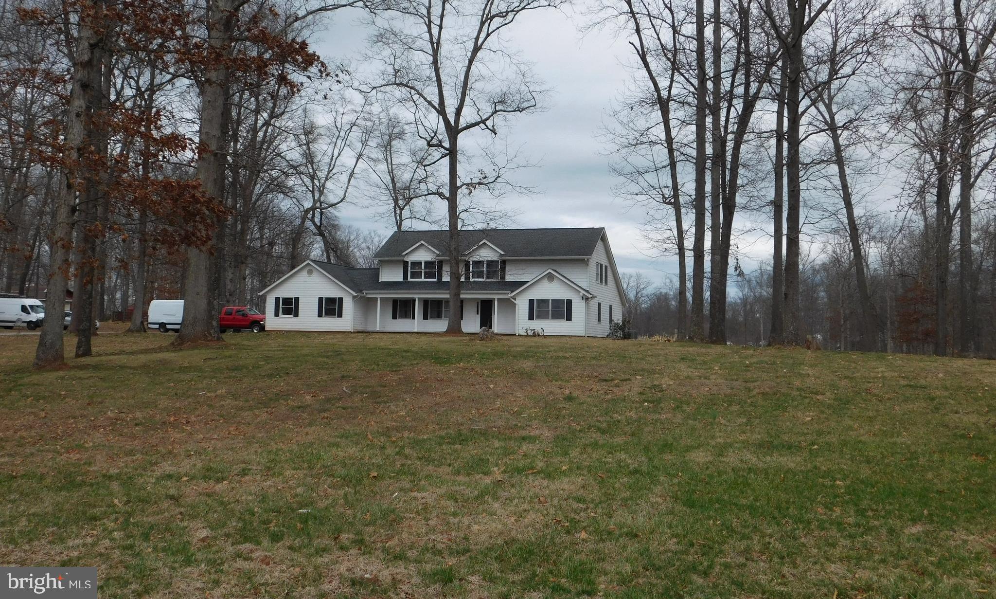 a white house with a big yard and large trees