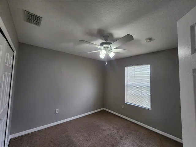 an empty room with closet and a ceiling fan