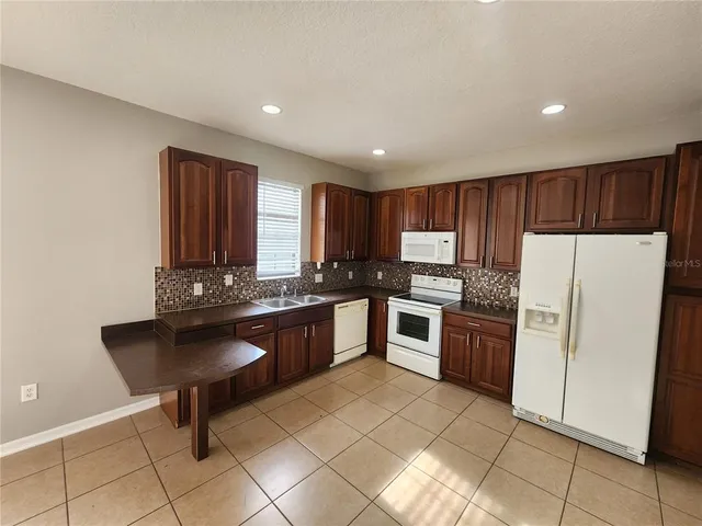 a kitchen with granite countertop a refrigerator and a stove top oven