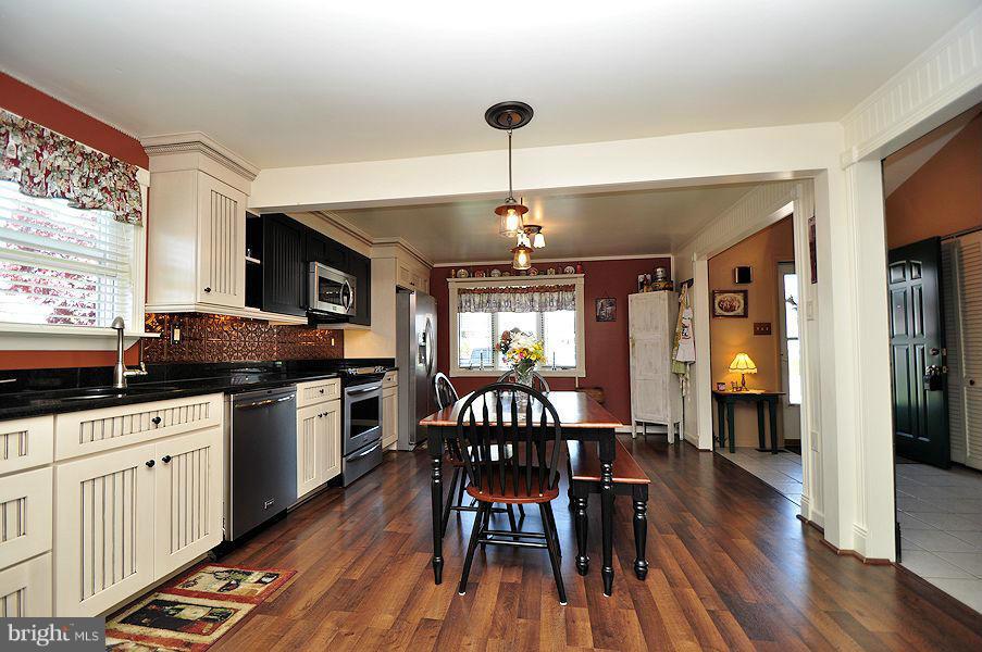 4813 Vicky Road Baltimore, MD 21236 - Photo 3 of 22 a kitchen with granite countertop a dining table chairs stainless steel appliances and wooden floor