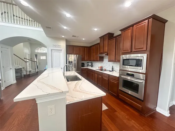 a kitchen with stainless steel appliances granite countertop a stove a sink dishwasher and a dining table with wooden floor