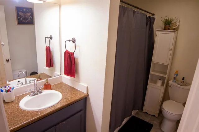 a bathroom with a granite countertop sink toilet and shower