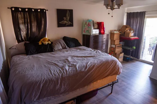 a bedroom with a bed a dresser and wooden floor