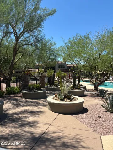 a swimming pool with some potted plants and large trees