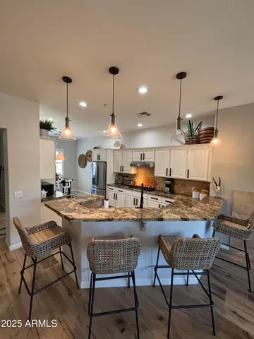 a dining room with stainless steel appliances kitchen island granite countertop a table chairs and a refrigerator