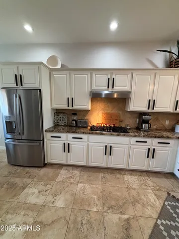 a kitchen with granite countertop a refrigerator and a stove top oven