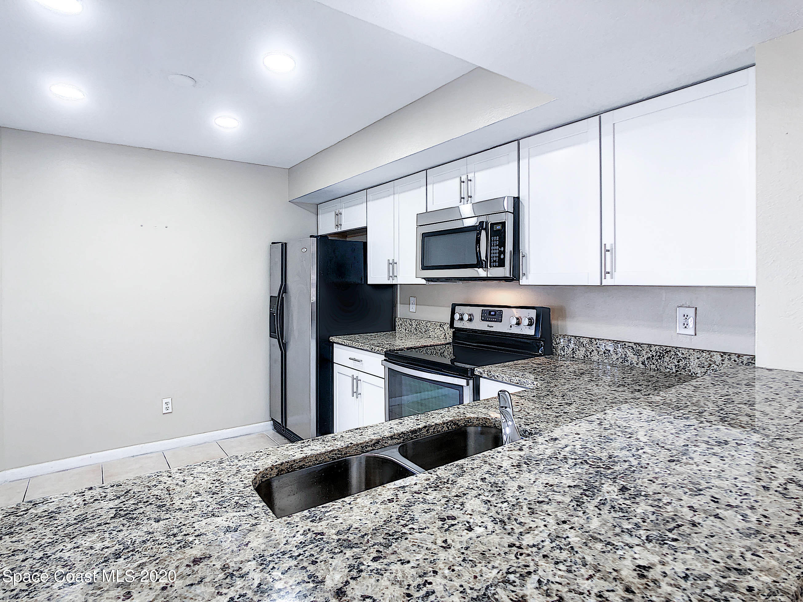 1882 Murrell Road, Unit 44 Rockledge, FL 32955 - Photo 6 of 27 a kitchen with granite countertop a stove a sink and a microwave
