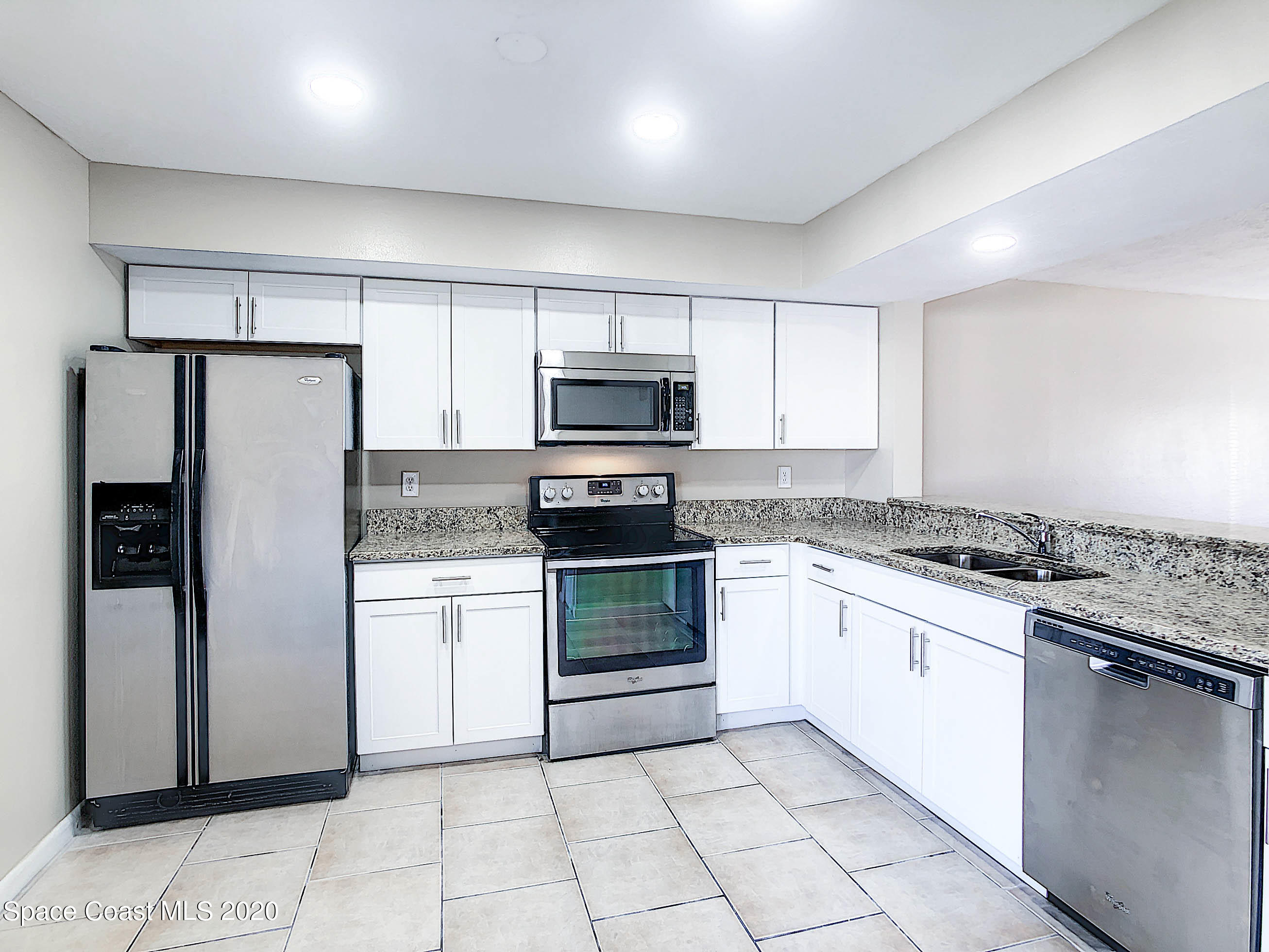 1882 Murrell Road, Unit 44 Rockledge, FL 32955 - Photo 8 of 27 a kitchen with granite countertop a refrigerator and a stove top oven