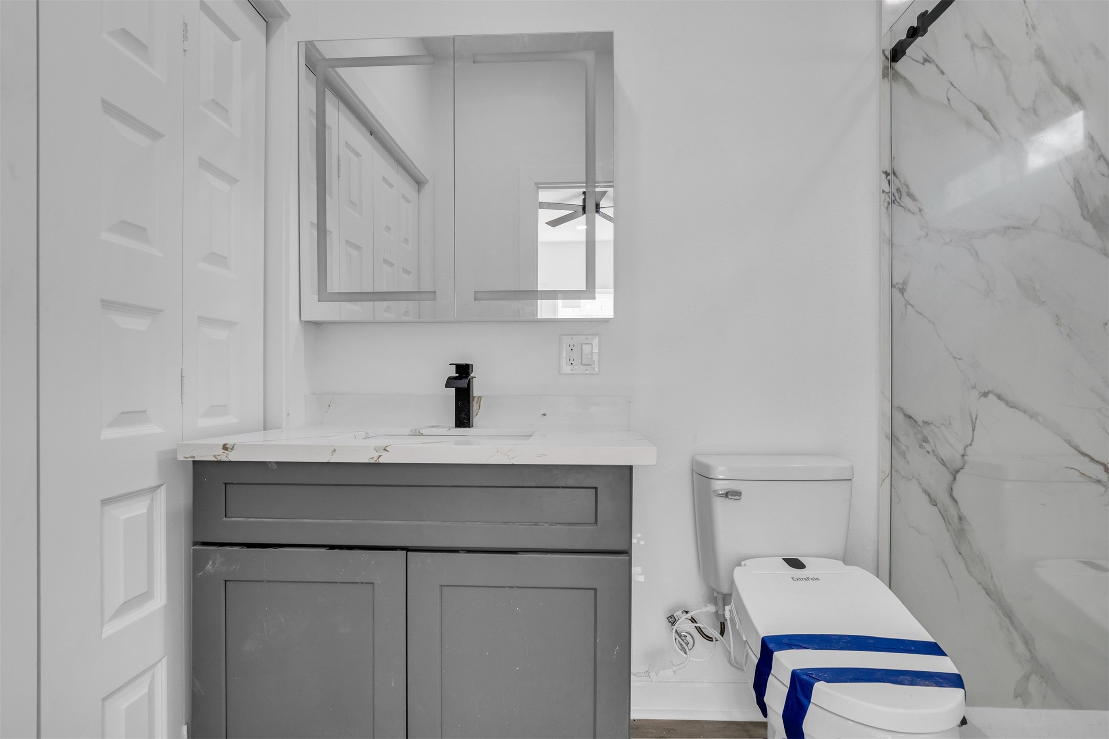 117 Rain Forest Road Onalaska, TX 77360 - Photo 26 of 30 Modern bathroom featuring a sleek marble-topped vanity, elegant gray cabinetry, and a spacious shower with a luxurious marble surround.