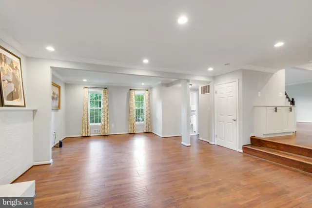 a view of an empty room with wooden floor and a fireplace