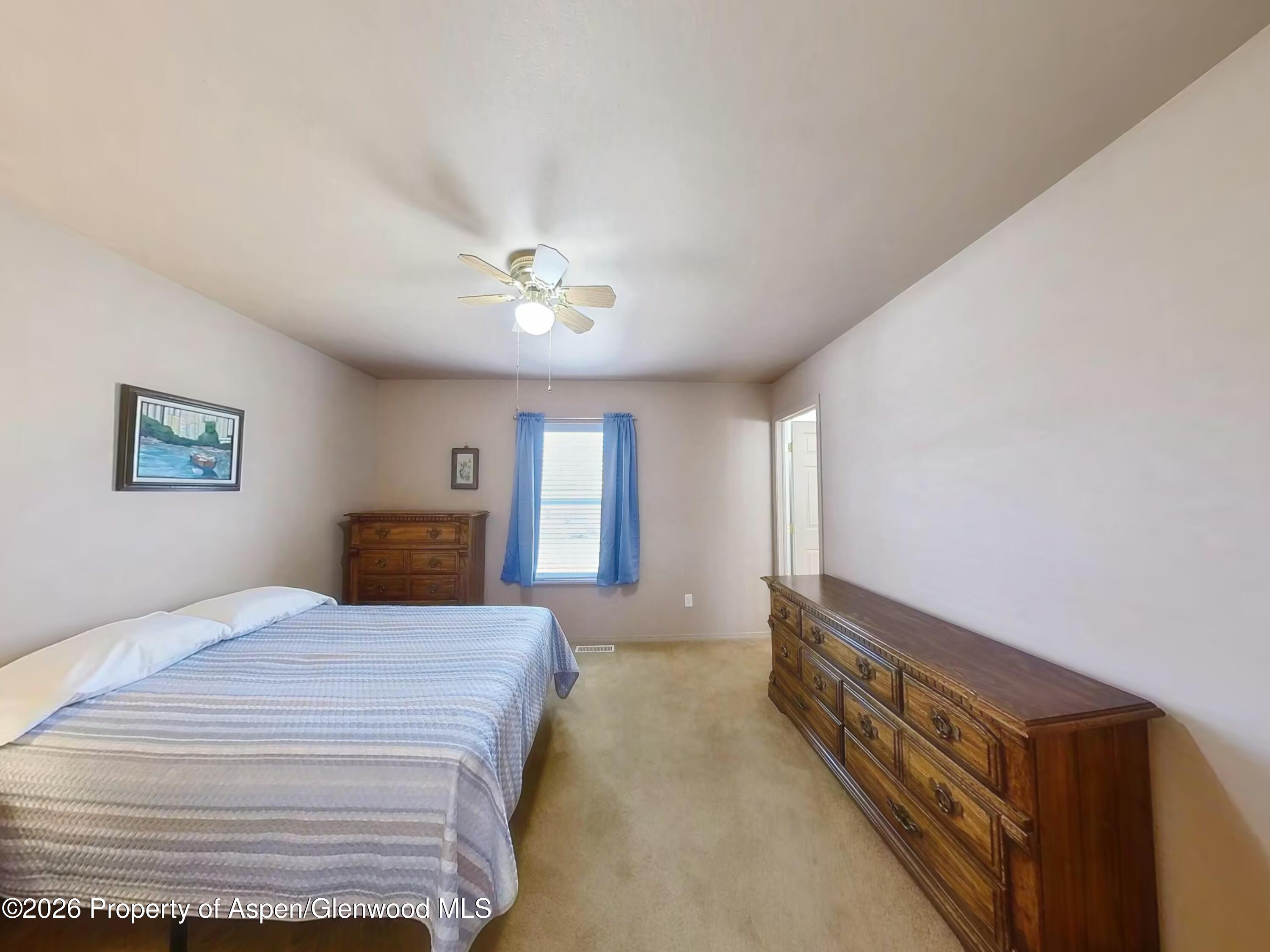 2319 Meadow Circle Rifle, CO 81650 - Photo 29 of 33 a spacious bedroom with a bed and a chandelier