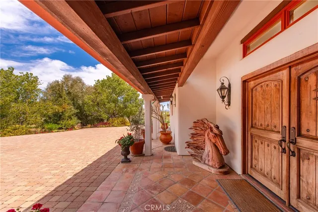 a balcony with table and chairs potted plants