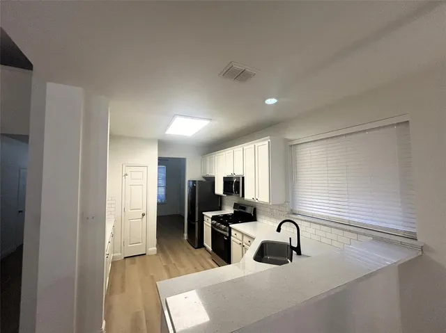 a large kitchen with a sink stainless steel appliances and cabinets