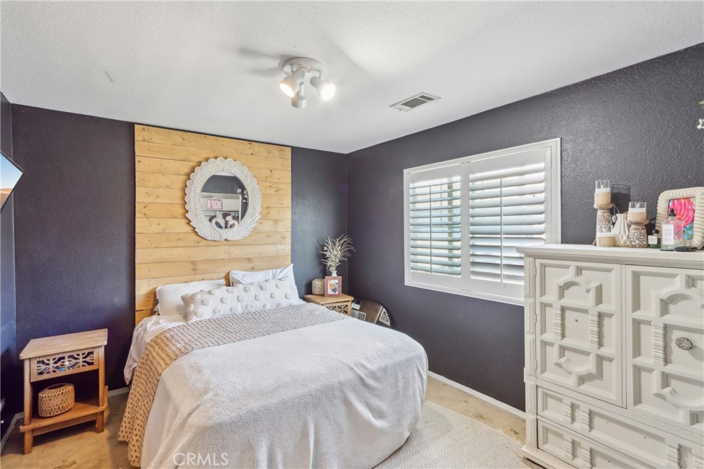 33971 Lily Road Yucaipa, CA 92399 - Photo 21 of 29 a bedroom with a bed and a chandelier