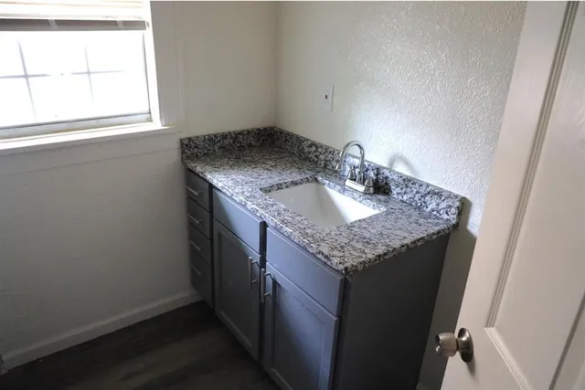 a bathroom with a granite countertop sink and a window