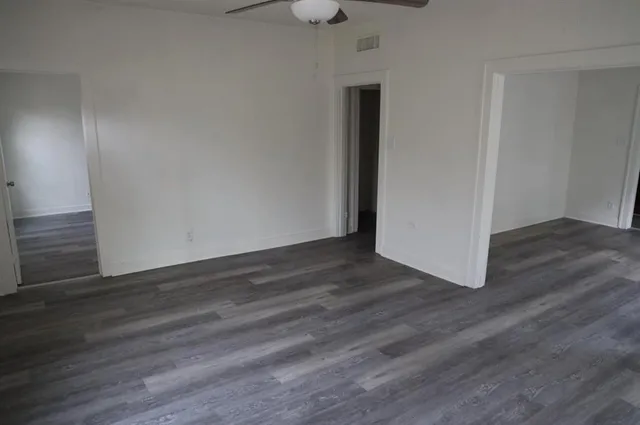 a view of an empty room with wooden floor and closet