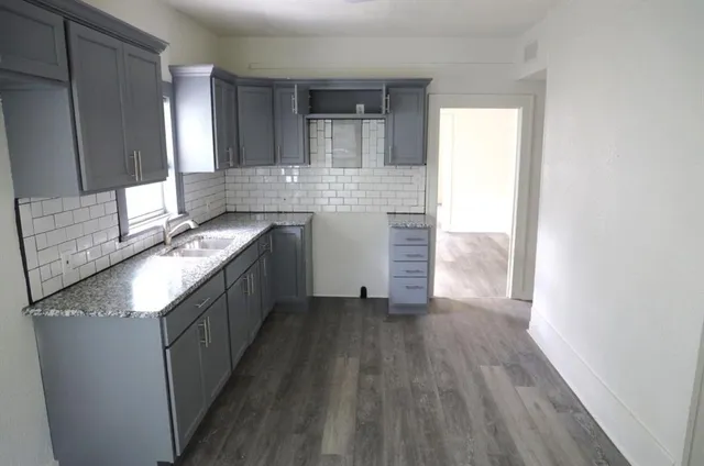 a kitchen with granite countertop a sink stove and cabinets