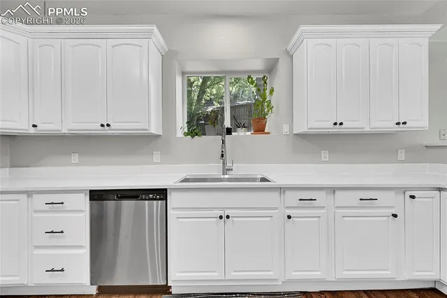 a kitchen with white cabinets and sink