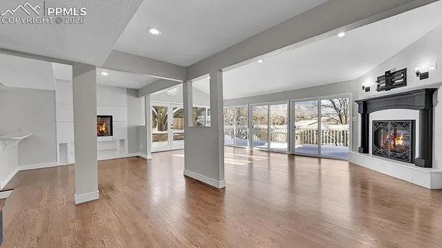 a view of an empty room with wooden floor and a fireplace