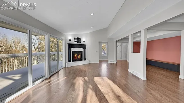 a view of empty room with wooden floor and fireplace