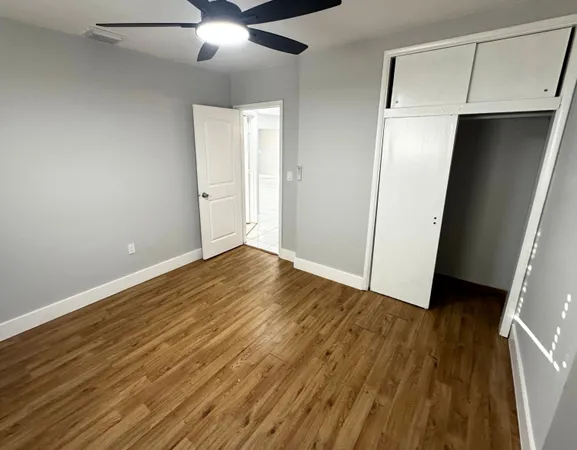an empty room with wooden floor and chandelier fan