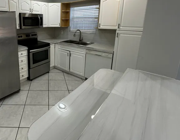 a kitchen with stainless steel appliances a sink cabinets and a window