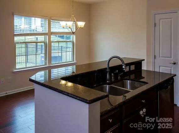a kitchen with stainless steel appliances granite countertop a refrigerator a stove and a sink with wooden floor