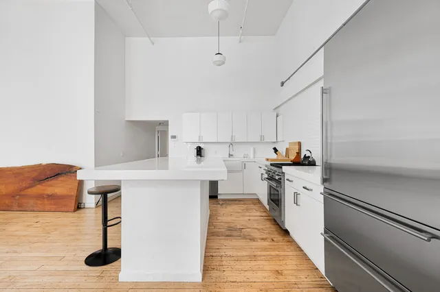 a kitchen with white cabinets stainless steel appliances and wooden floor