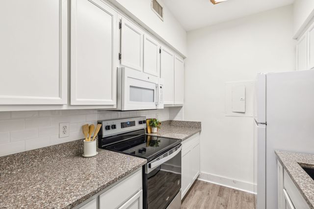 a kitchen with granite countertop a sink stove and cabinets