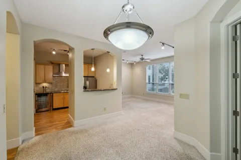 a view of a hallway with wooden floor and a kitchen