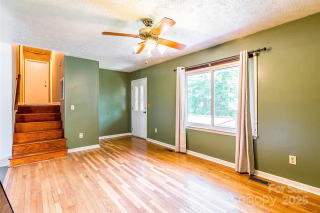 a view of a room with wooden floor a ceiling fan and window