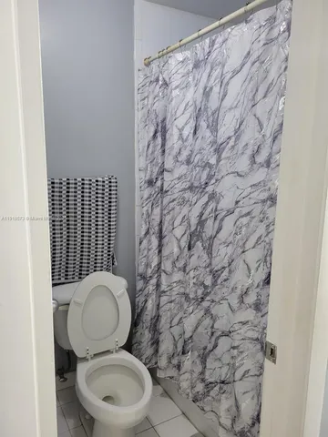 a white toilet sitting next to a shower curtain