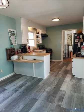 a room with kitchen island a sink a stove and wooden floor