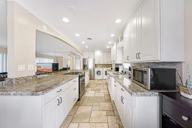 a large kitchen with stainless steel appliances granite countertop a large counter top and a stove